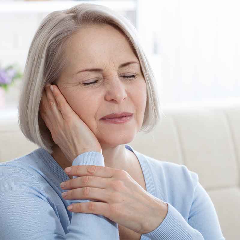 Woman with tinnitus holding her ear.